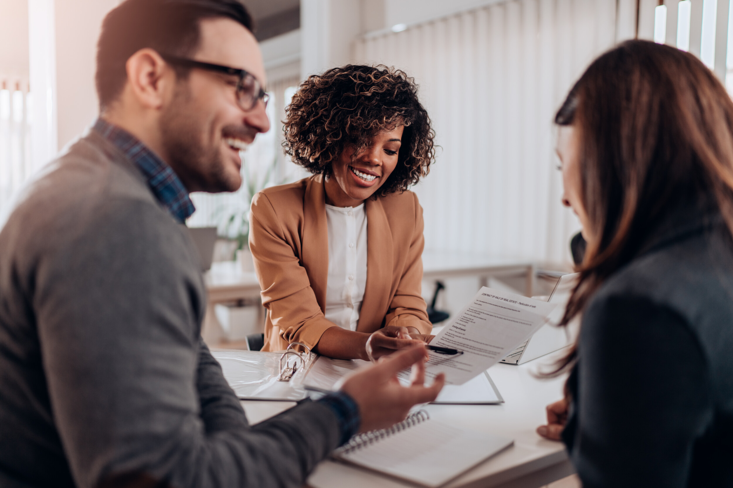 3 people talking to each other at an office desk with papers on it